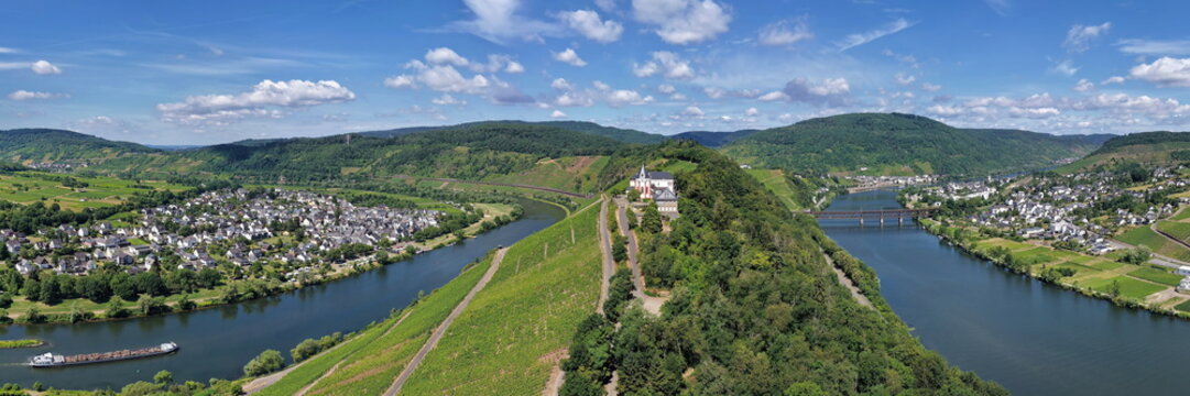 Spektakul&auml;re Drohnenaufnahme der historischen Marienburg auf dem schmalen Bergr&uuml;cken der Moselschleife bei Zell, umgeben von sonnigen Weinh&auml;ngen.