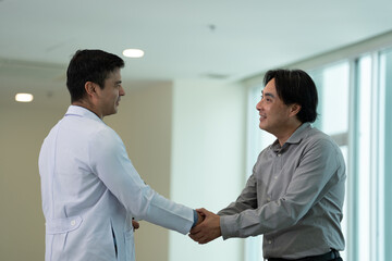 Doctor greeting patient with handshake during medical consultation in hospital corridor in bright clinical setting © Stock Media Labs