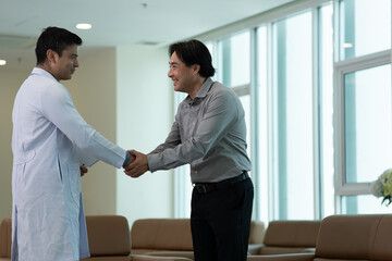 Doctor greeting patient with handshake during medical consultation in hospital corridor near bright window © Stock Media Labs