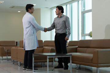 Doctor greeting patient with handshake during medical consultation in hospital waiting room near bright window © Stock Media Labs
