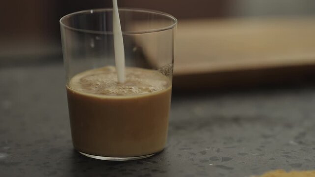 Pour milk into glass with shot of espresso