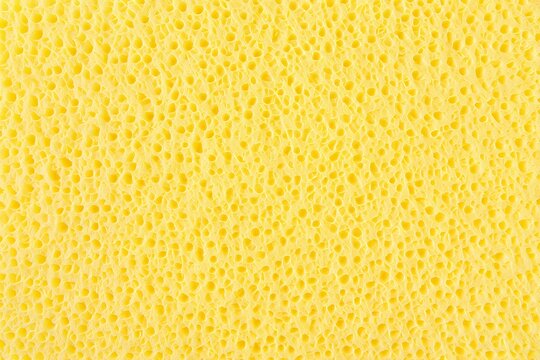 Yellow sponge texture background, porous absorbent material surface, macro cellular foam pattern, bright yellow cleaning sponge backdrop