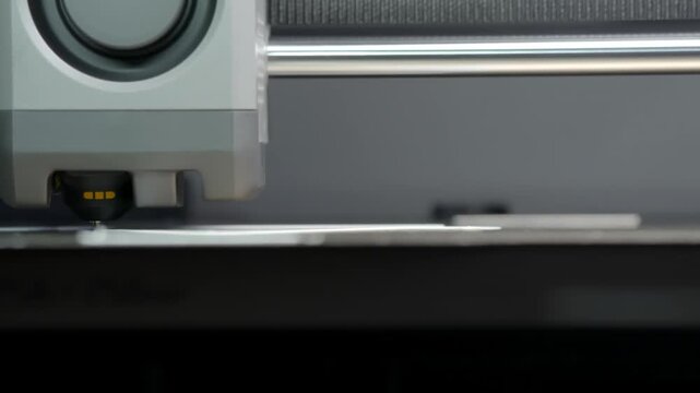 Metallic structure with circular speaker component. Gray casing holds precise audio hardware. Modern design showcases sleek, functional audio equipment