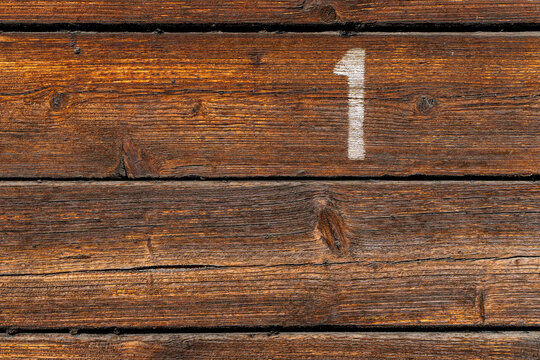 Dark weathered wooden planks with white number one