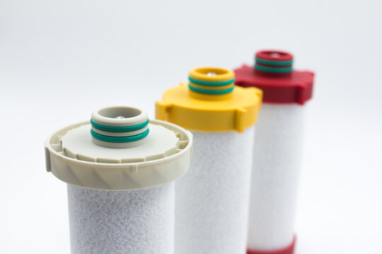Compressed air inline filter element replacement cartridges on white background. Studio shot of three high-efficiency coalescing and particulate filter element cartridges for compressed air line syste