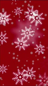 Delicate white snowflakes of varying sizes drift gently across rich deep red background, creating warm festive winter atmosphere.