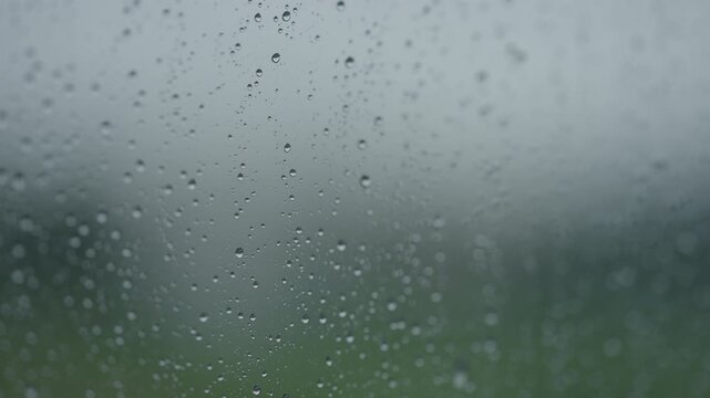Rain drop hitting window glass and sliding down