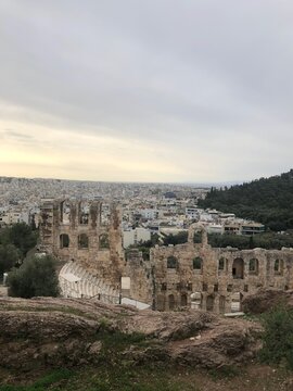 Ancient Odeon of Herodes Atticus stone theatre with scenic Athens cityscape view from the Acropolis, Greece. Historical Roman amphitheater landmark under cloudy sky