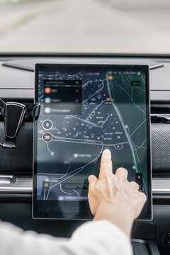 Woman using car navigation touchscreen with GPS map in modern vehicle interior