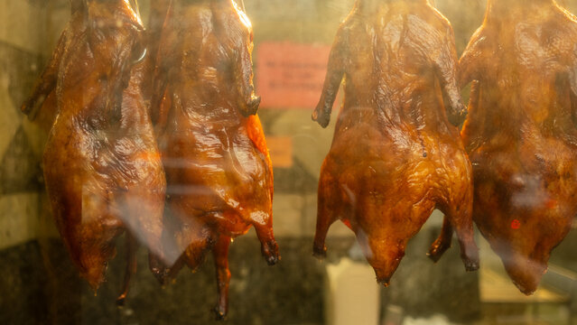 Roasted ducks hanging behind a shop window