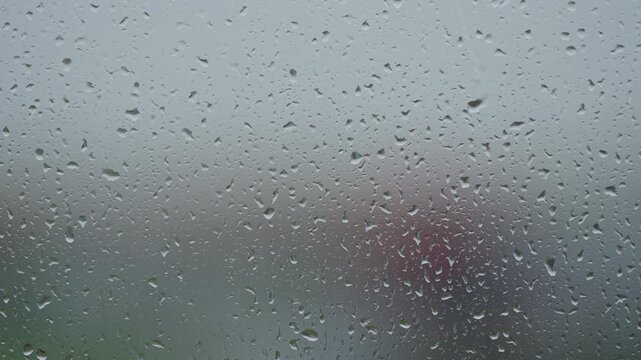 Rain drop hitting window glass and sliding down