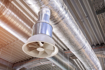 Industrial air conditioning system featuring metal ducts and a large fan, providing climate control and airflow in a modern building © EdNurg