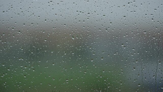 Rain drop hitting window glass and sliding down