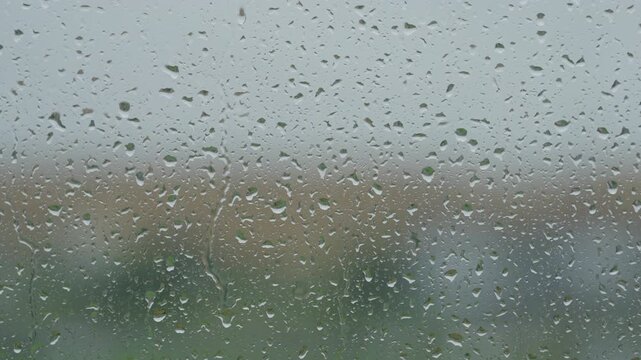 Rain drop hitting window glass and sliding down