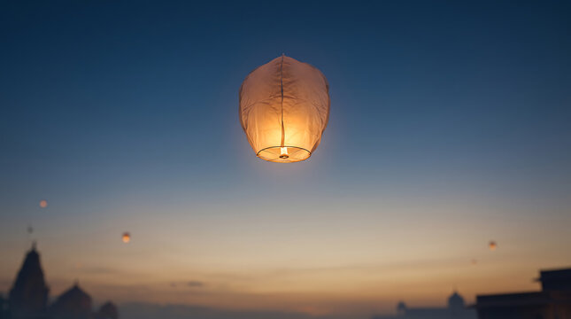 A single paper lantern floating in the evening sky