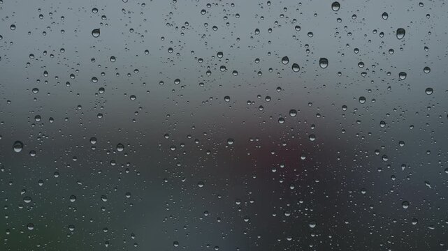 Rain drop hitting window glass and sliding down
