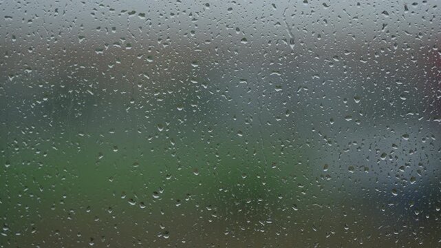 Rain drop hitting window glass and sliding down