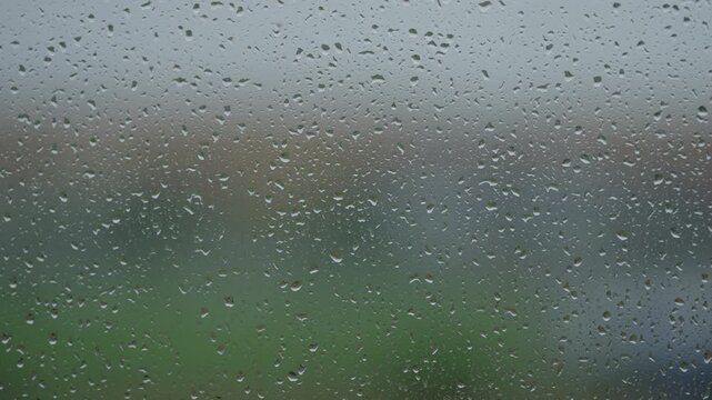 Rain drop hitting window glass and sliding down