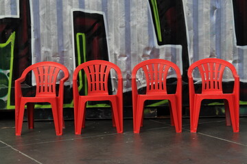 Naklejka premium Four Red Plastic Chairs on a Row