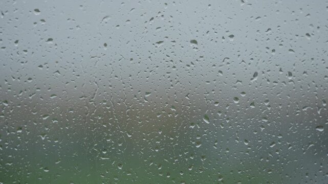 Rain drop hitting window glass and sliding down
