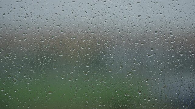 Rain drop hitting window glass and sliding down