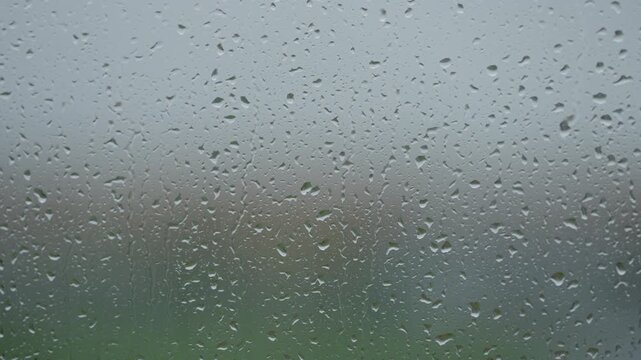 Rain drop hitting window glass and sliding down