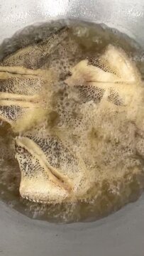 Close up of crispy whole gourami fish (pla salid) deep fried in hot boiling oil in a pan, traditional Thai home cooking and delicious local food.