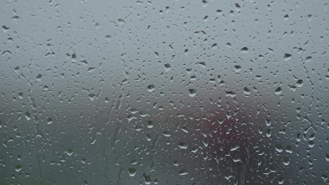 Rain drop hitting window glass and sliding down