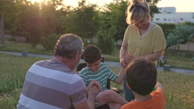 Family bonding with disabled child in wheelchair at sunset