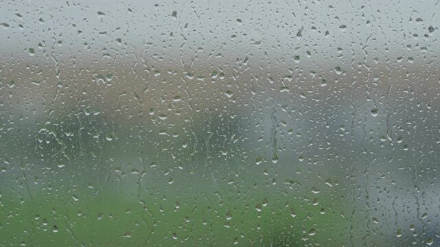 Rain drop hitting window glass and sliding down
