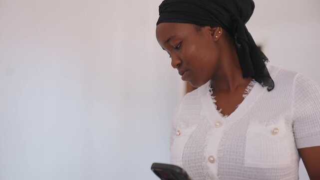Close up view shows woman holding device against simple light colored backdrop. subject remains in frame with minimal movement smartphone headshot indoor