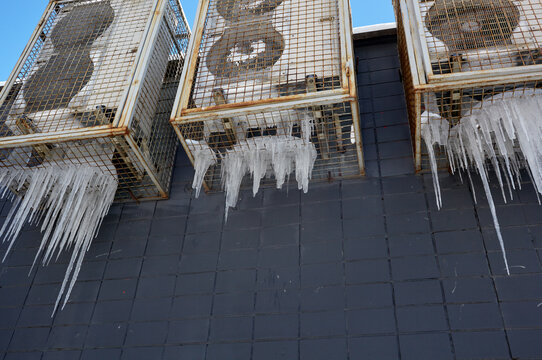 Three frozen outdoor air conditioner units covered with icicles