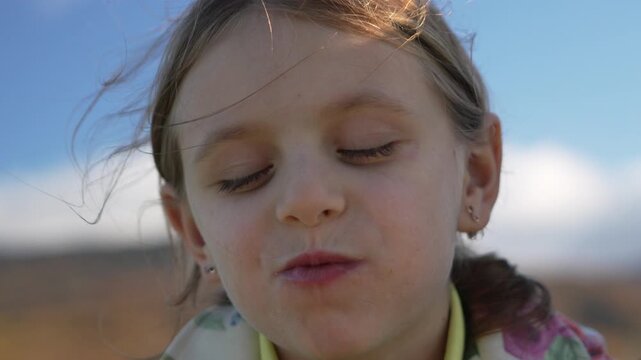 Child eating snack outdoors, young girl enjoying leisure time food under clear blue sky