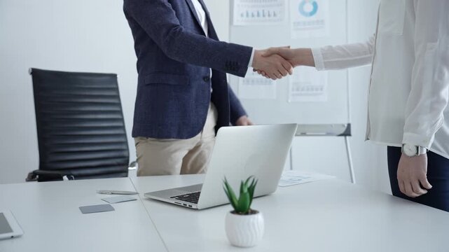 Business people shaking hands in a bright modern office, finalizing a partnership agreement, showing successful corporate collaboration and professional relationship building