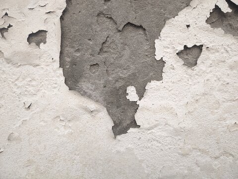 Closeup view of peeling and deteriorating old wall surface showing texture and damage patterns