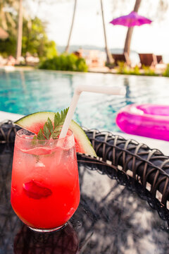 Watermelon soda cocktails on table with blurred poolside and beach background. Summer drinks concept.