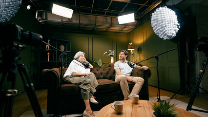 Obraz premium Two people creating a podcast, broadcasting their interview in a professional studio setting with microphones and camera