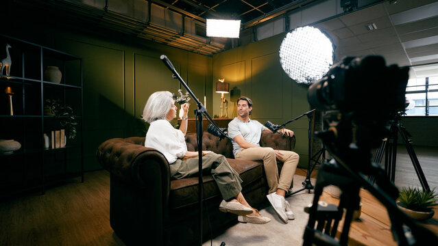 Two diverse podcasters sitting on a sofa in a studio setting, creating engaging audio and video content