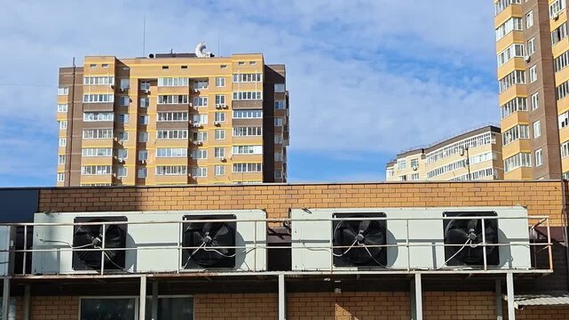 Four outdoor air conditioning units running with spinning fans in horizontal row