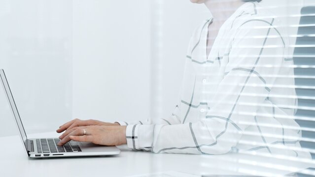 Business person working remotely or in a modern office. Typing on a laptop keyboard. Focusing on digital tasks. Achieving productivity and professional goals