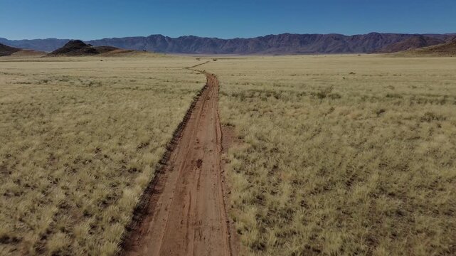 A drone flies over a narrow, deserted road and the dusty savanna in Namibia (Africa)