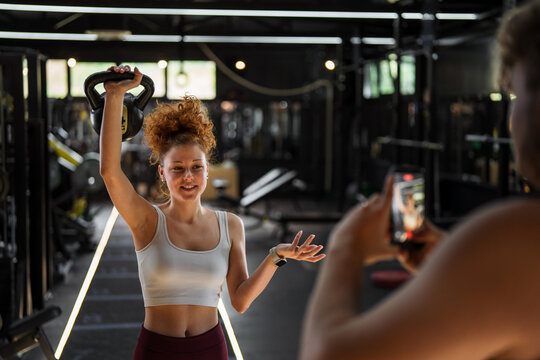 Woman influencer creating fitness content with kettlebell in gym
