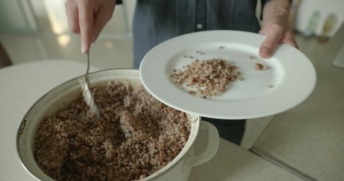 Close-up male hand put buckwheat on plate dish. 4K 10-bit