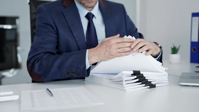 Professional businessman handling documents, reviewing paperwork, organizing files, managing administrative tasks, and dealing with bureaucracy in a corporate office setting
