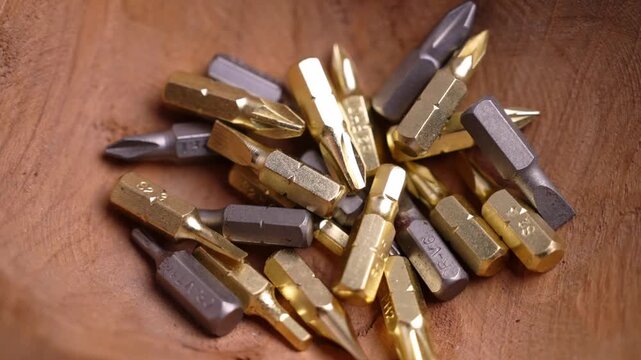 Assorted screwdriver bits falling into a rustic wooden bowl. Pozidriv, Torx and slotted heads. Craftsmanship concept