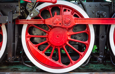 Close-up of red driving wheel and connecting rod of a vintage steam locomotive © eos200