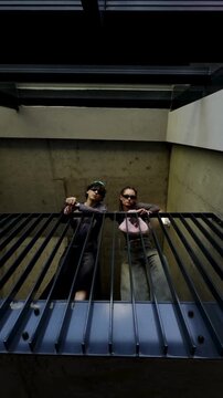 Two friends looking down through metal grate from above in urban underground space