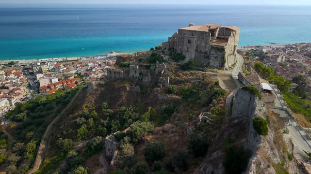 Authentic villages of Italy Hidden gems Calabria. Roccella Ionica  borgo cinematic footage Castello Carafa medieval castle tower close proximity backward drone reveal turquoise Ionian sea 4k video