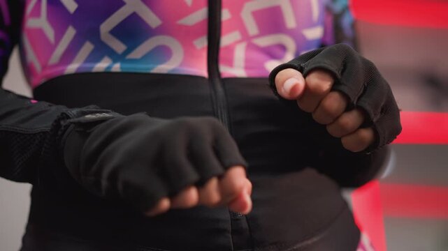 Close up view shows person gloved hands executing precise slow paced exercises focusing on grip strength. subject wears fingerless gloves and colorful athletic wear with abstract patterns