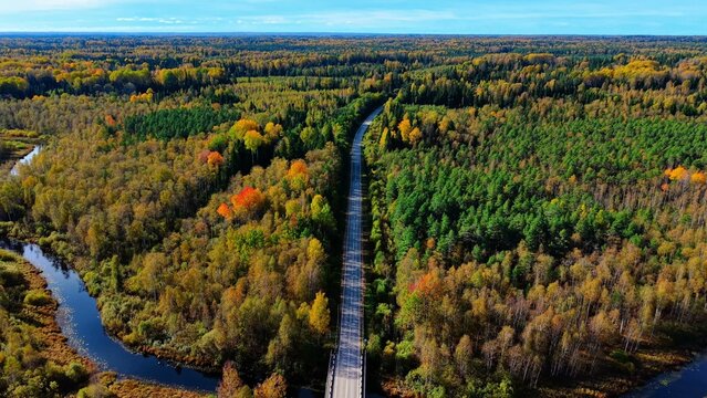 Aerial view of railway bridge surrounded by vibrant autumn foliage and winding river